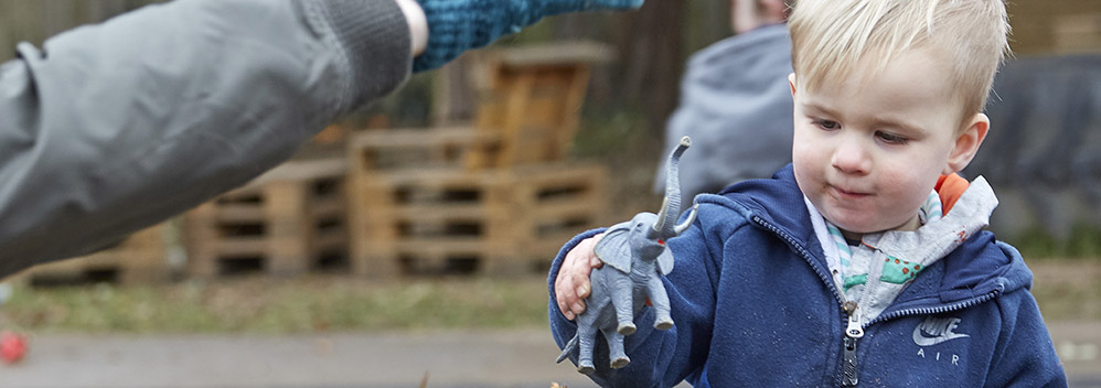 little boy playing with a toy elephant