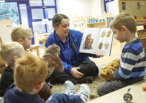 Westside Day Nursery worker reading a book with children