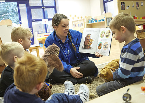 nursery worker reading a boy to children