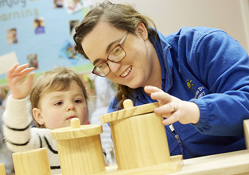 nursery worker putting lids on wooden pieces